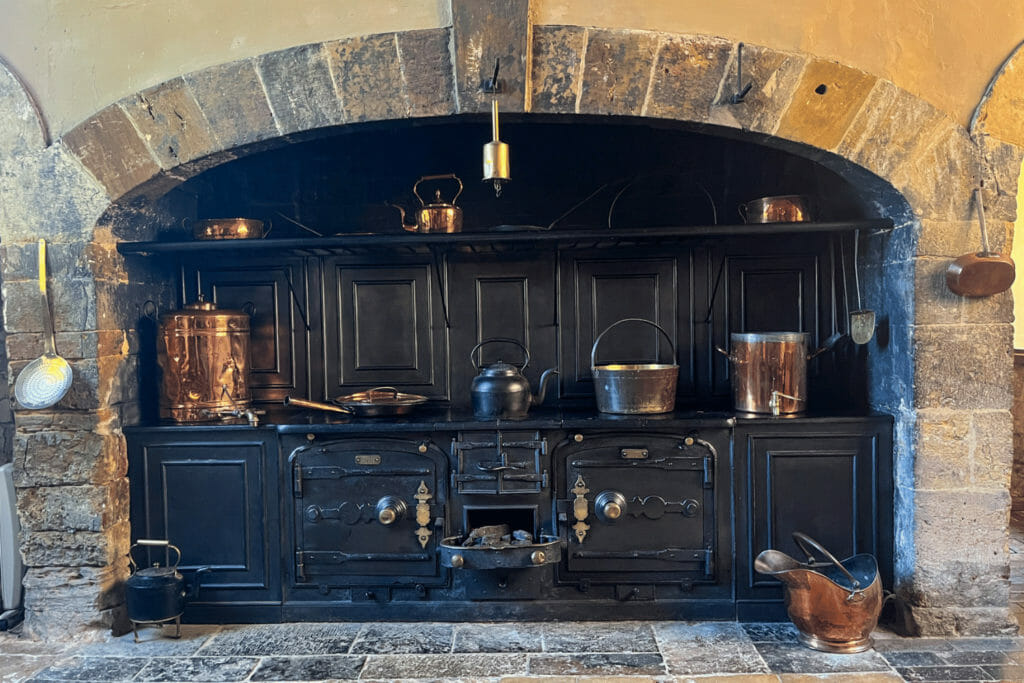 Black range kitchen inside a brick archway with pots, pans and utensils.