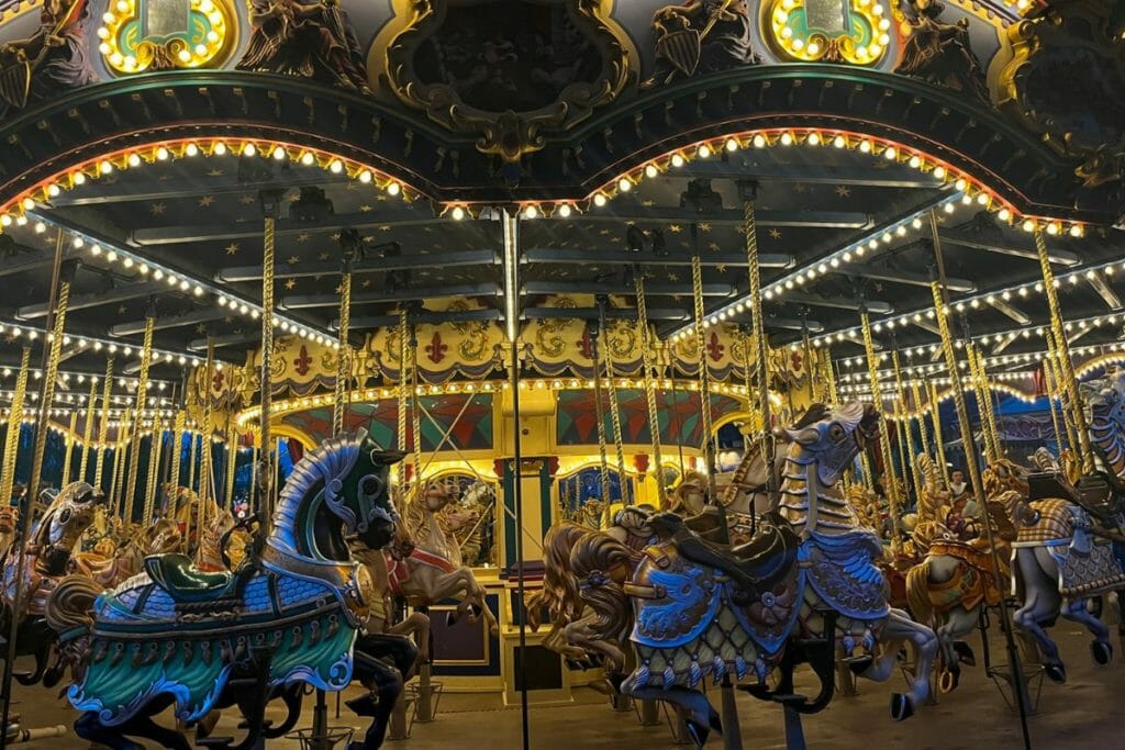 1 Disneyland Paris Carousel A brightly lit carousel at Disneyland Paris, filled with ornately decorated horses and riders, illuminated by numerous twinkling lights against a night sky.